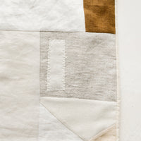 3: A rectangular placemat with patchwork design in natural shades.
