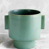 1: A ceramic planter in turquoise glaze with straight side tabs.