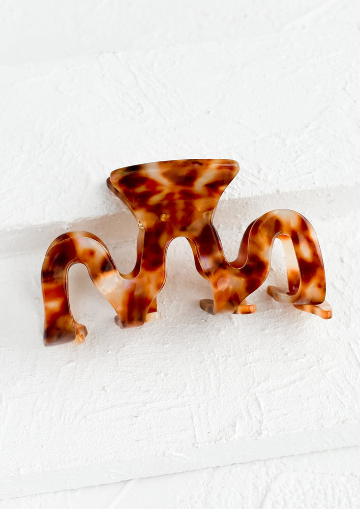 An acetate hair clip in squiggle shape in brown marble.