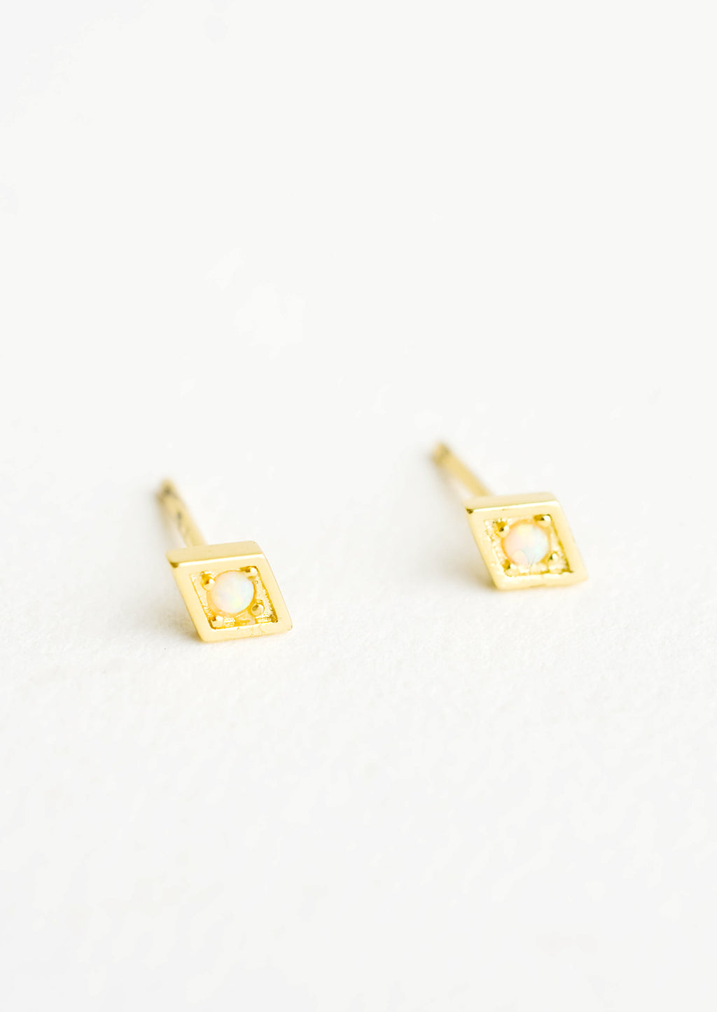 Diamond: Diamond shaped stud earrings in gold finish, with small round opal stone inset.