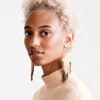 2: Model shot wearing beaded earrings and a peach top.