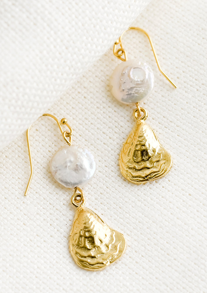 A pair of earrings with pearl disc and oyster shell.
