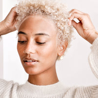 2: Model shot showing woman wearing earrings and white sweater.