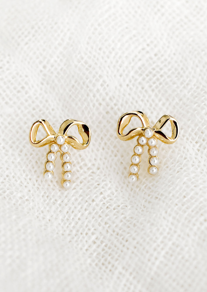 1: A pair of gold bow studs with tiny pearl detailing on "strings".