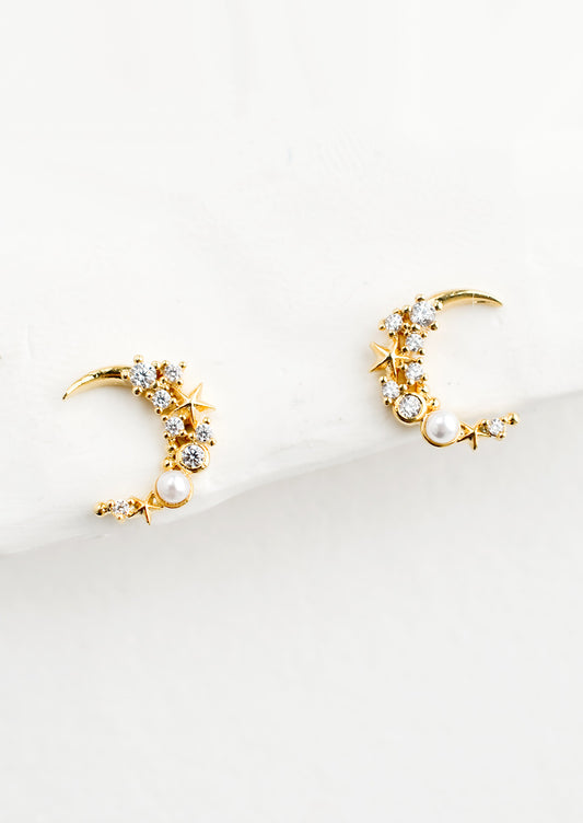 A pair of gold crescent moon shaped earrings with crystal and pearl detailing.