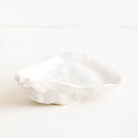2: A small, pearly white ceramic dish molded in the shape of an oyster half shell