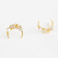 2: A pair of gold crescent moon shaped earrings with crystal and pearl detailing.
