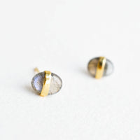 1: Oval-shaped, pebble-like stud earrings in iridescent labradorite with golden band wrapped around middle.