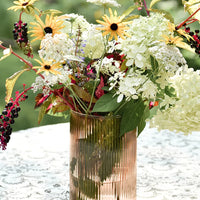 2: A ribbed peach glass vase with floral arrangement.