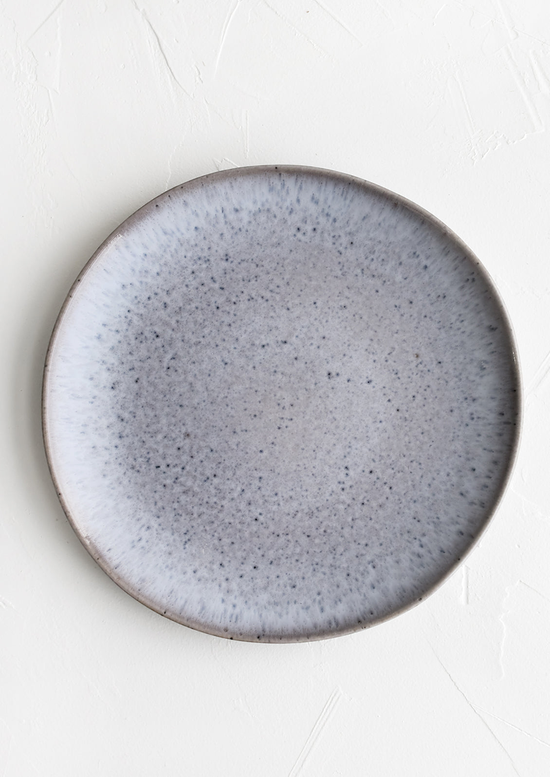 A round ceramic dinner plate in speckled periwinkle glaze.