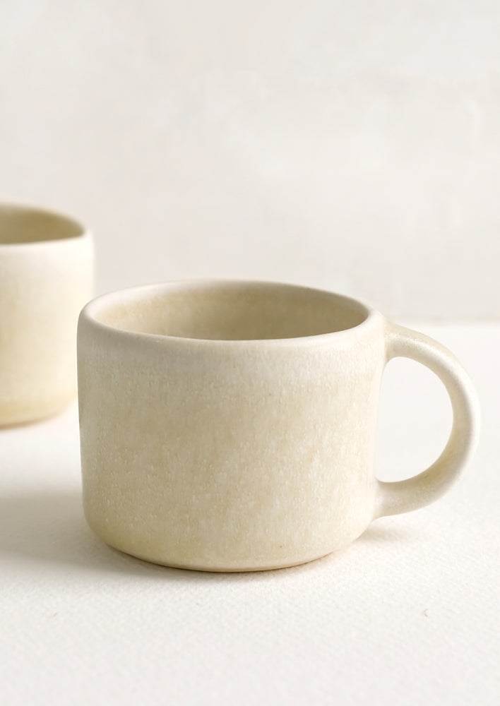 A ceramic espresso mug with handle in neutral ivory glaze.