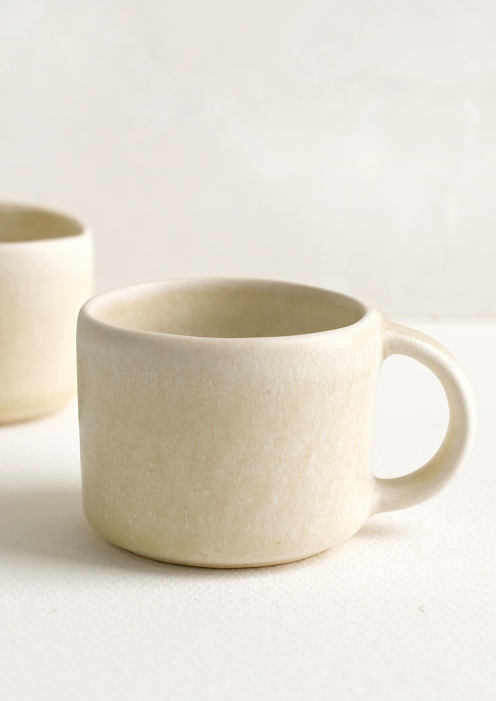 1: A ceramic espresso mug with handle in neutral ivory glaze.