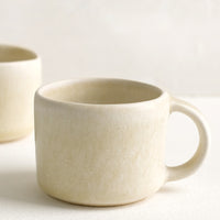 1: A ceramic espresso mug with handle in neutral ivory glaze.