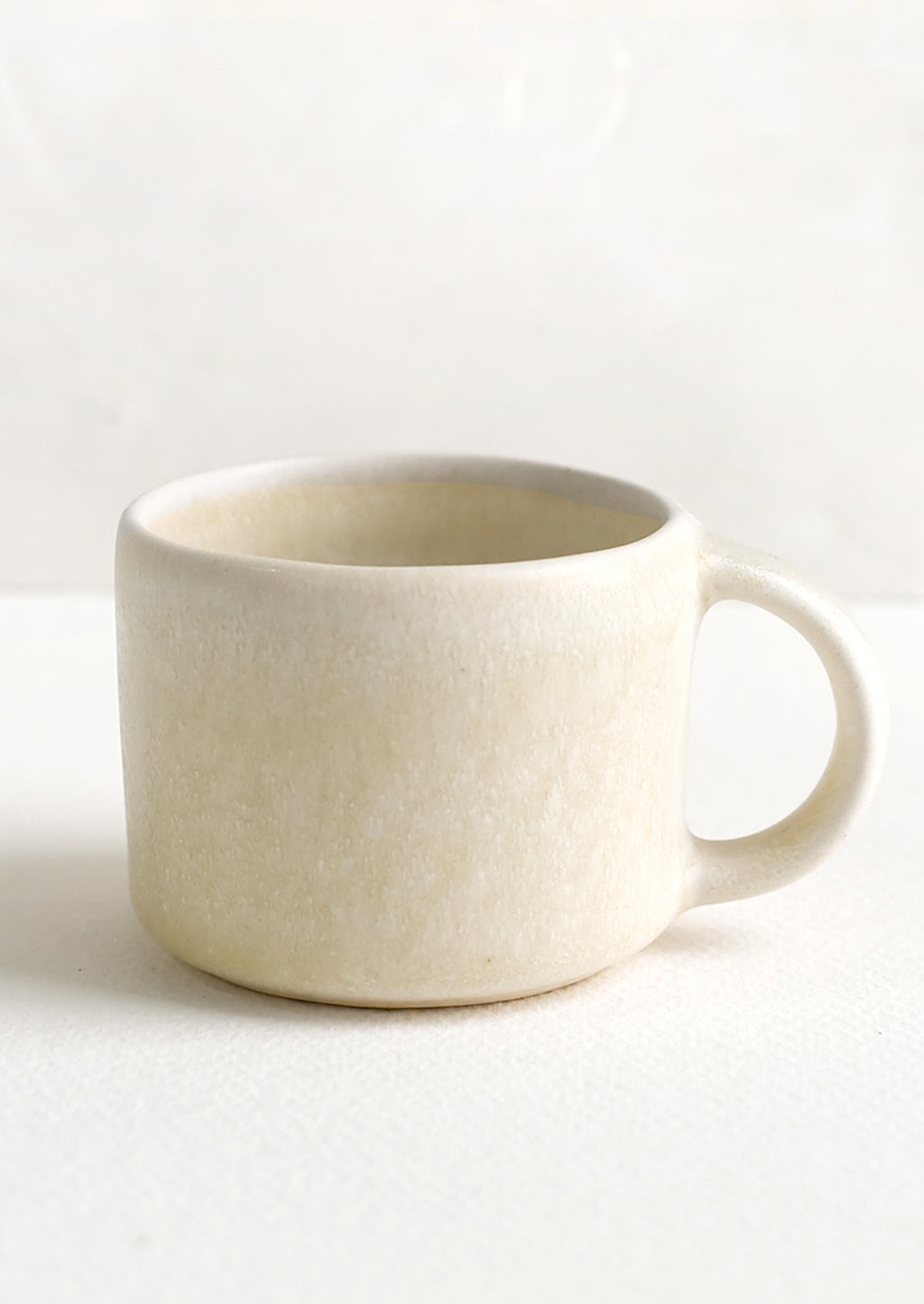 2: A ceramic espresso mug with handle in neutral ivory glaze.