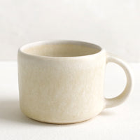 2: A ceramic espresso mug with handle in neutral ivory glaze.