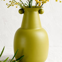 2: A lime green vase with mimosa flowers.