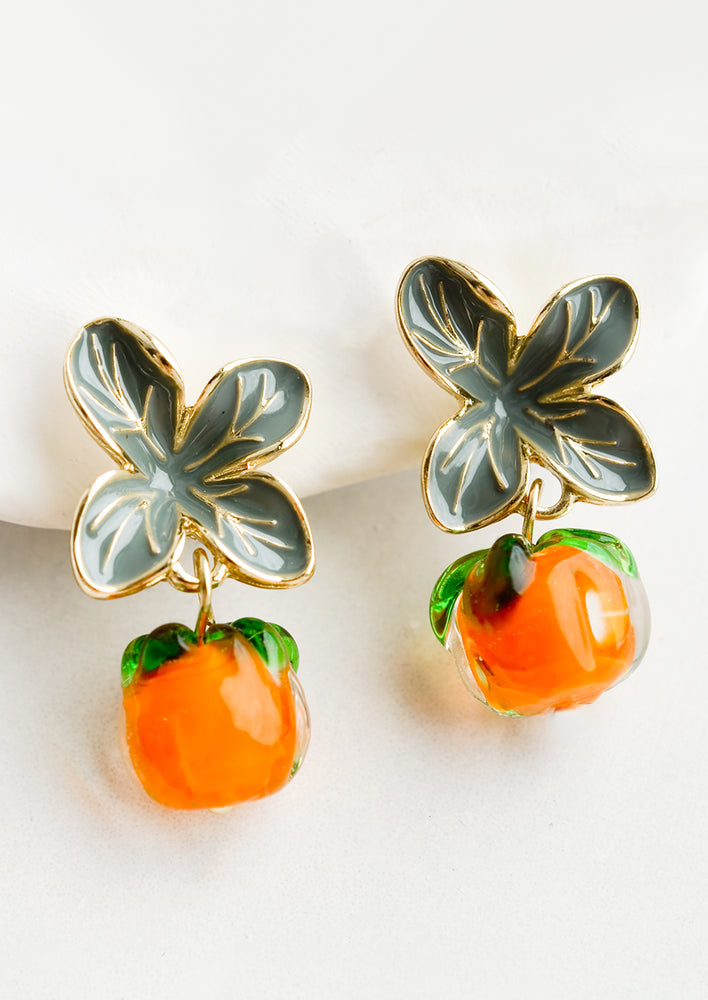A pair of earrings with glass persimmon charms and leaf shape post.