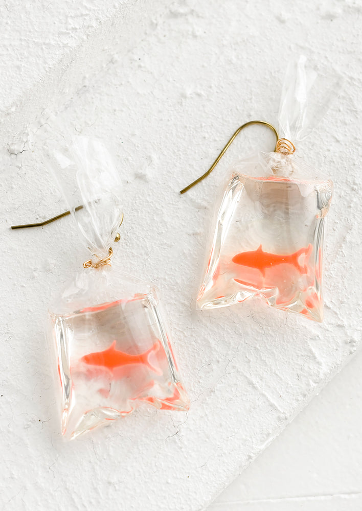 A pair of earrings with clear plastic bag with goldfish shape inside.