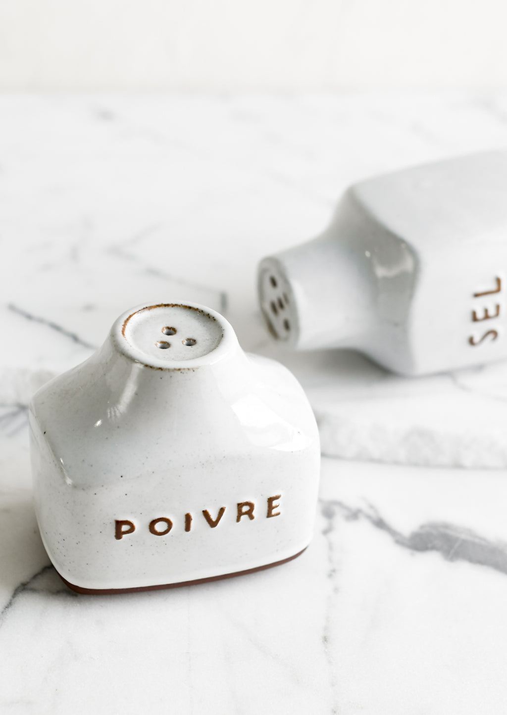 1: Ceramic salt and pepper shakers with text detail in French.
