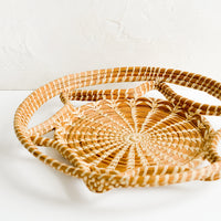 2: A round, flat tray with curved open weave design.