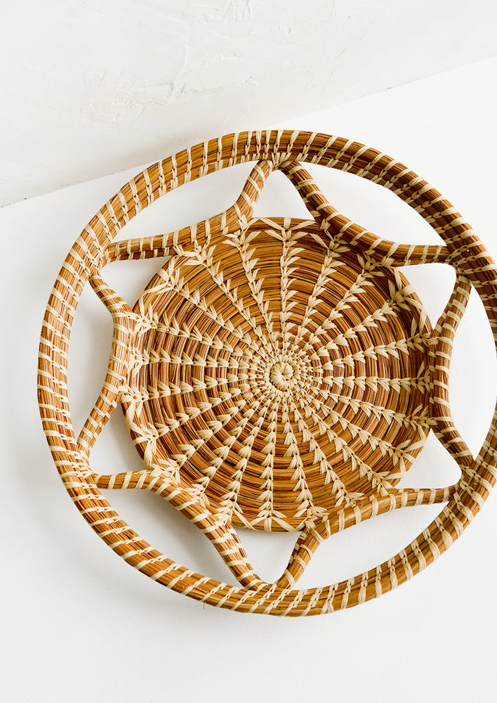 A round, flat tray with curved open weave design.
