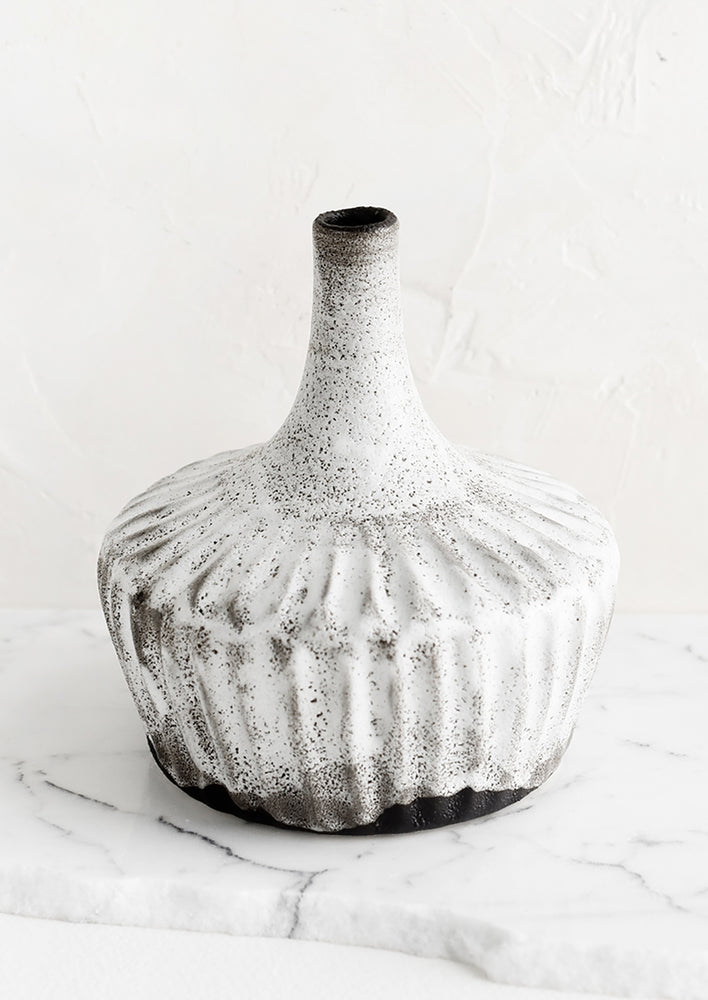 A ceramic vase in rustic white glaze over dark clay, with narrowed opening.