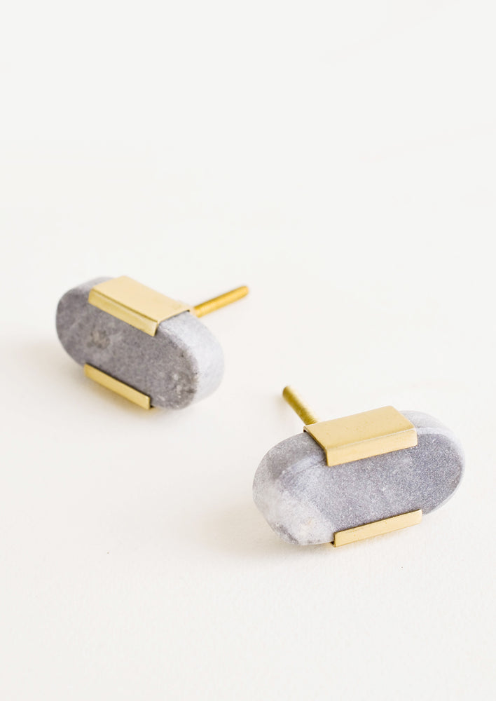 Pill shaped cabinet knob made in solid grey marble with brass accents