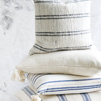 5: A stack of pillows in white, blue and cream colors.
