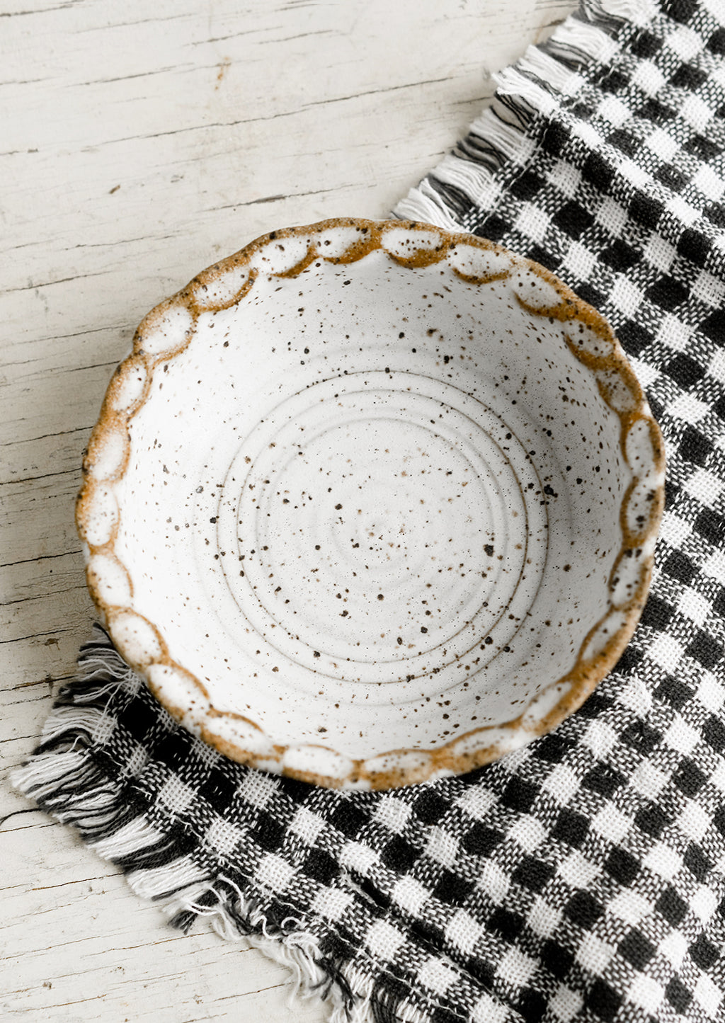 2: A small ceramic bowl with pinched rim in speckled white glaze.
