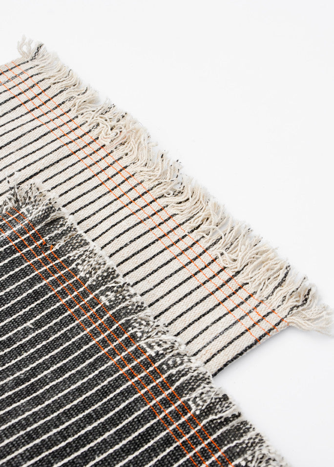Table runners with frayed edges. Black and white pinstripe with orange stitching detail.