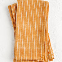 2: Folded fabric napkins in a pile featuring orange and white pinstripe pattern.