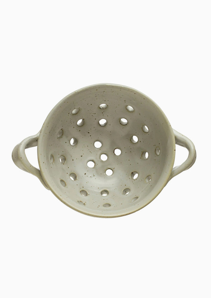 A small speckled ceramic berry colander with side handles.