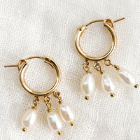 1: A pair of gold hoop earrings with three dangling pearls on each.