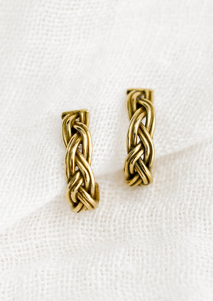 1: A pair of braided brass earrings that curve at bottom.
