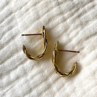 3: A pair of braided brass earrings that curve at bottom.