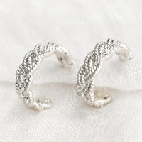 1: A pair of silver-tone hoop earrings with braided texture.