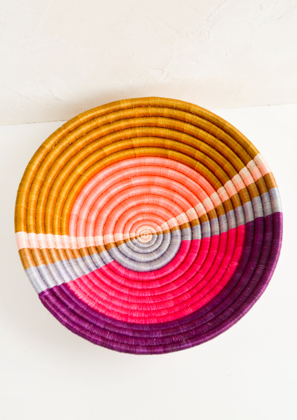1: A round colorful woven sweetgrass basket with multicolor sunset design.