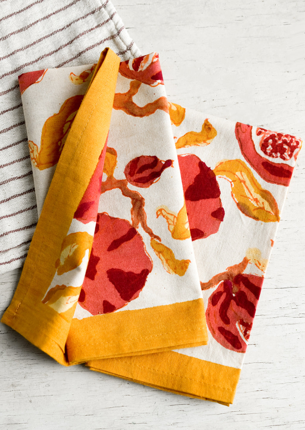 1: A pair of red and yellow pomegranate patterned cotton napkins.