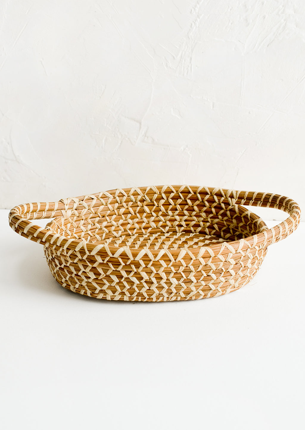 2: A shallow, oval shaped basket with handles at sides.