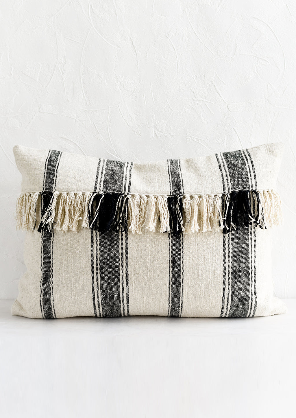 1: A lumbar throw pillow in natural cotton with vertical black stripes and horizontal fringe.