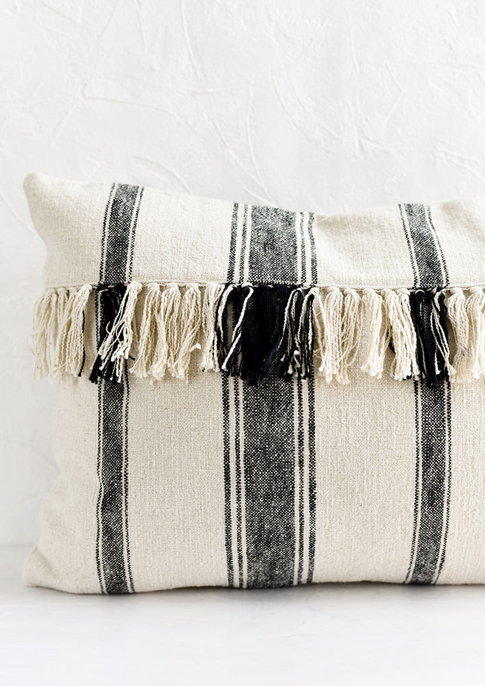 2: A lumbar throw pillow in natural cotton with vertical black stripes and horizontal fringe.