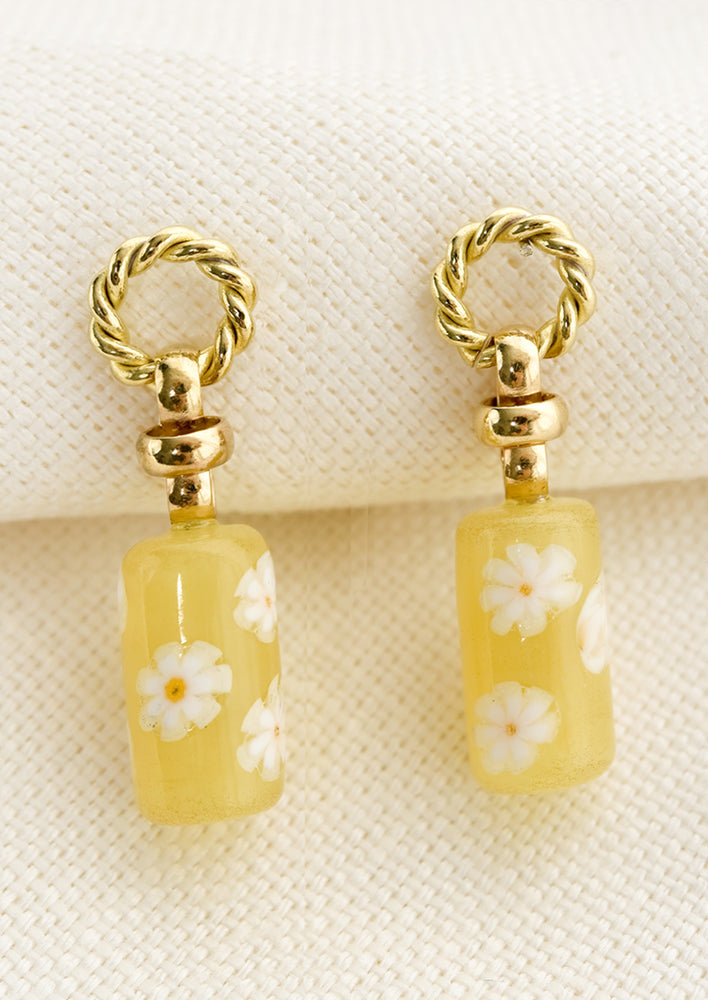 Lemon: A pair of earrings with circular braided brass post and yellow floral glass bead.