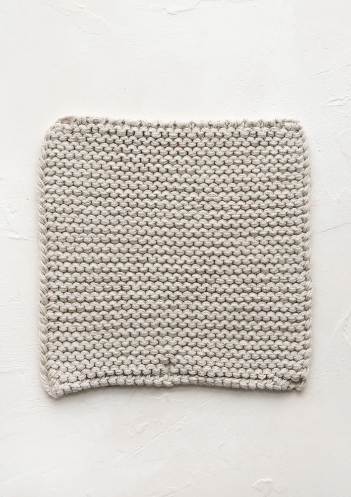 A square, chunky knit cotton potholder in oyster grey.