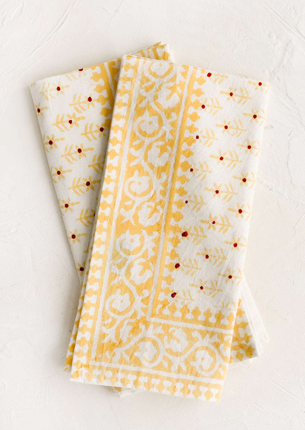 1: A pair of block printed napkins with yellow and red floral print.