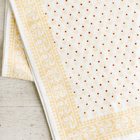 1: A cotton tablecloth in yellow and red floral block print motif.