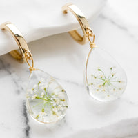 White / Green: A pair of earrings with gold huggie hoop and clear resin drop with encased white and green florals.