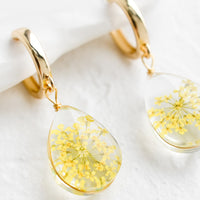 Yellow: A pair of earrings with gold huggie hoop and clear resin drop with encased yellow florals.