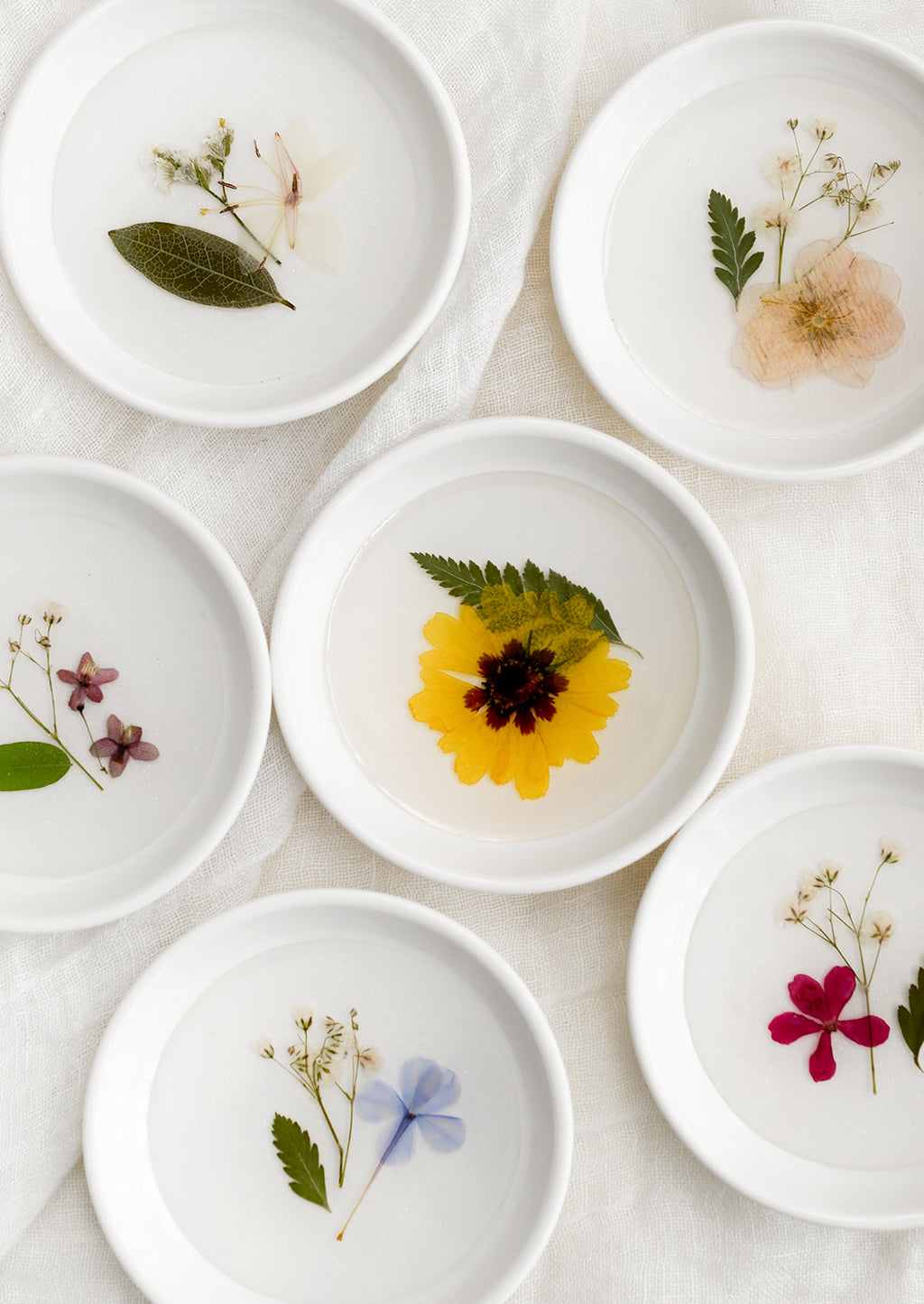 1: Assorted pressed flower ring dishes in white.