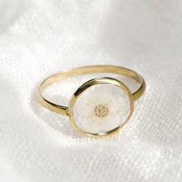 1: A gold round bezel ring showing white flower on clear background.