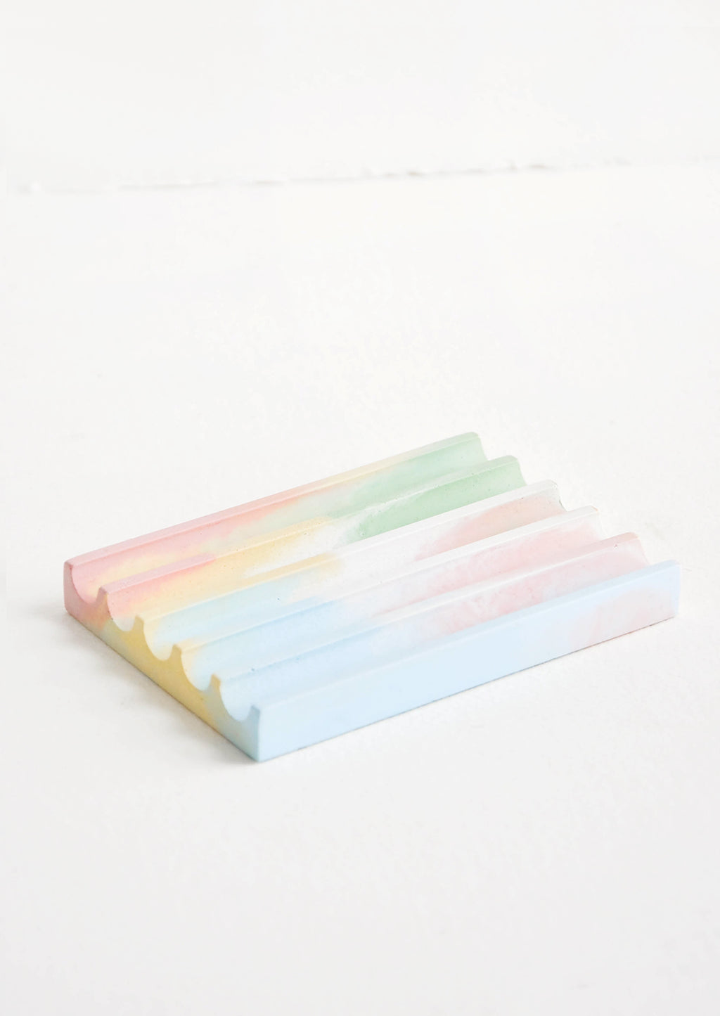 Rainbow: A marbled pink, yellow, blue, and green smooth concrete soap dish with troughs and ridges.